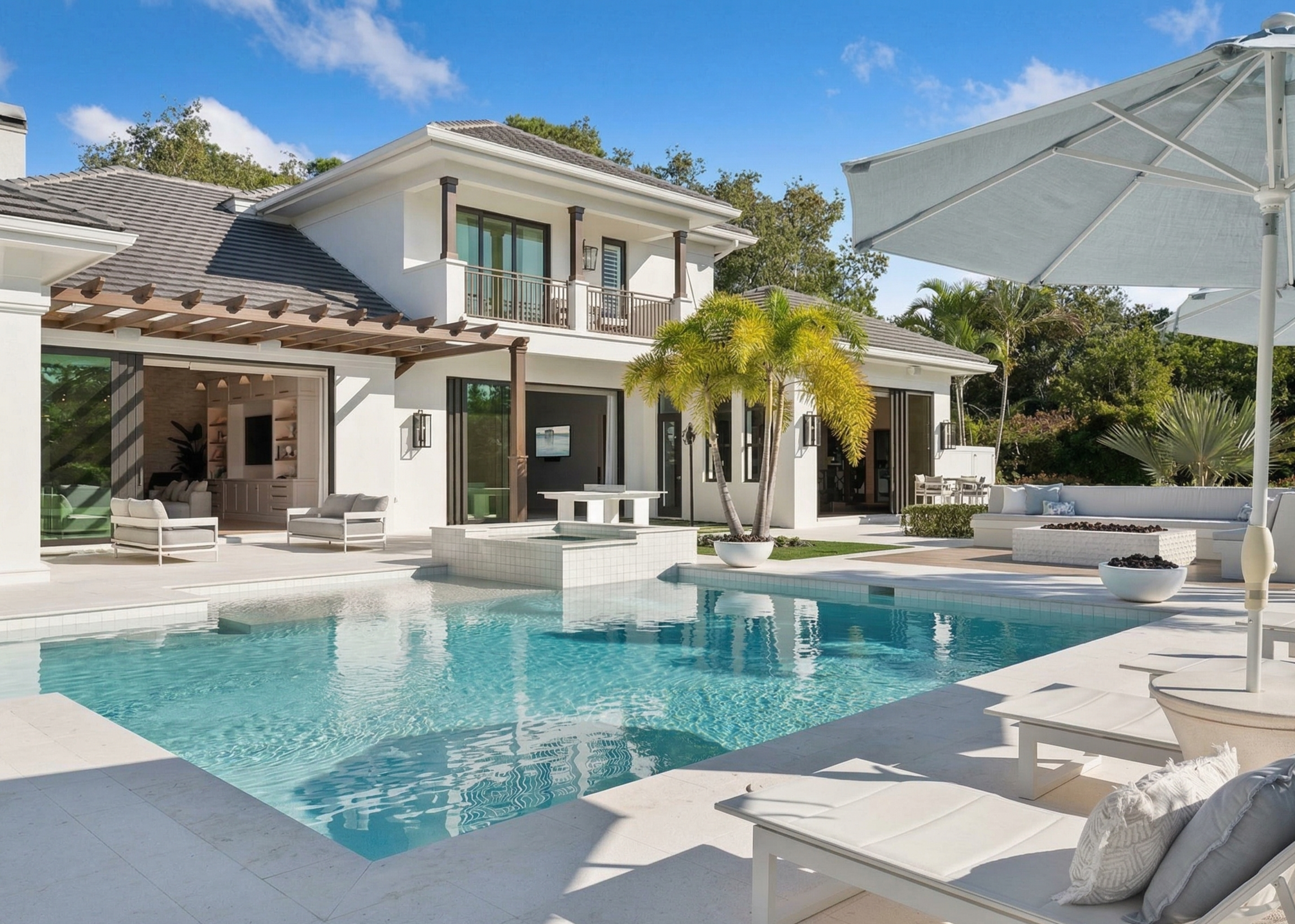 Luxury pool and spa in North Naples backyard with modern home, palm trees, and resort-style outdoor living area